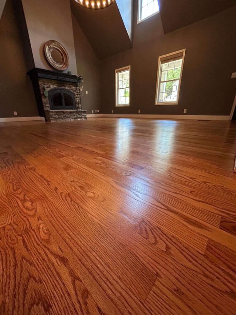 Warm wood flooring across a living room with a fireplace