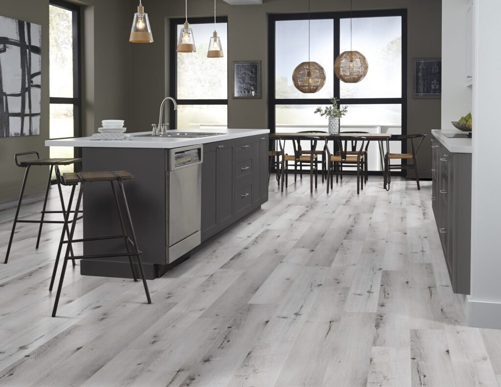 Kitchen with light wood flooring, dark island, and large windows