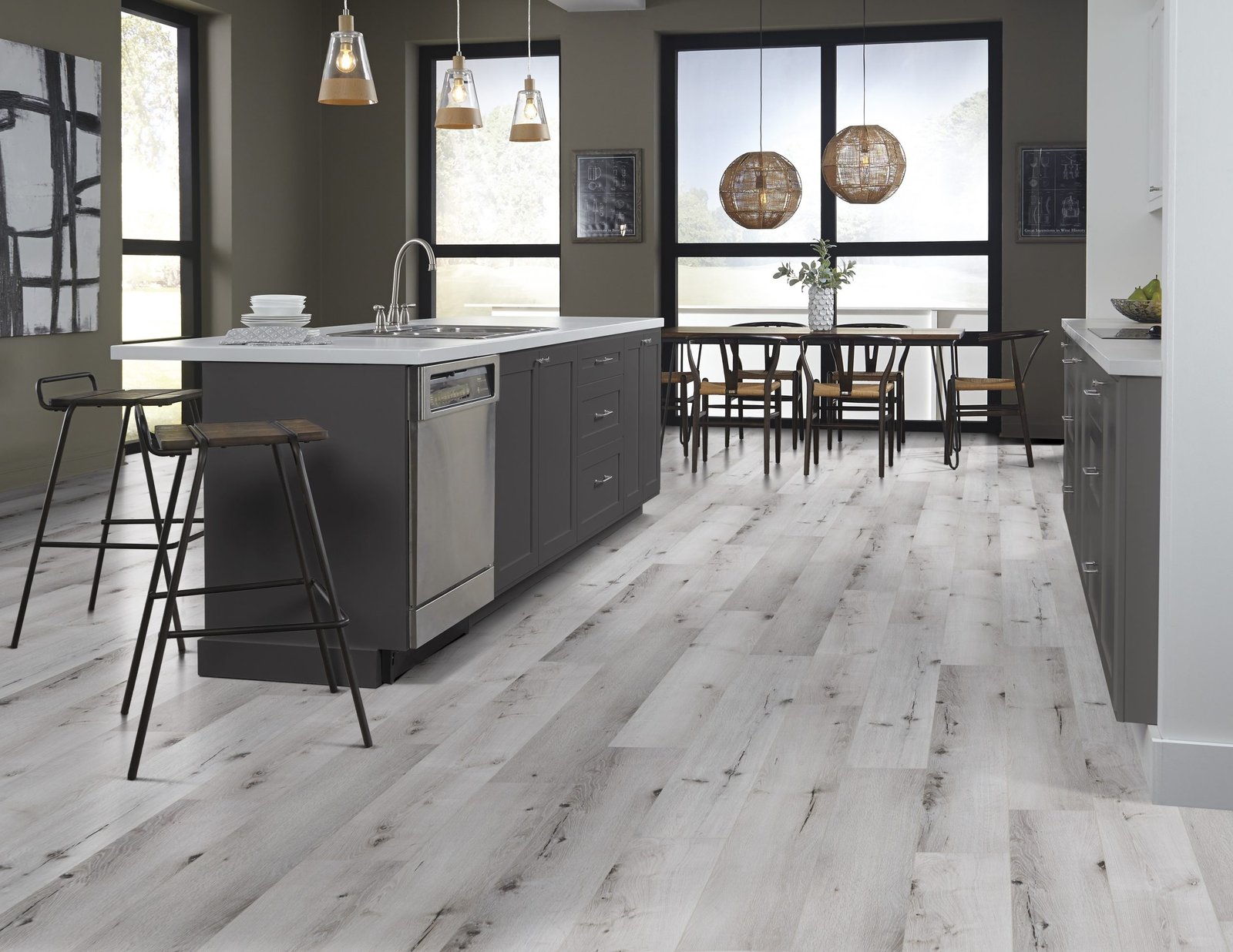 Kitchen with light wood flooring, dark island, and large windows