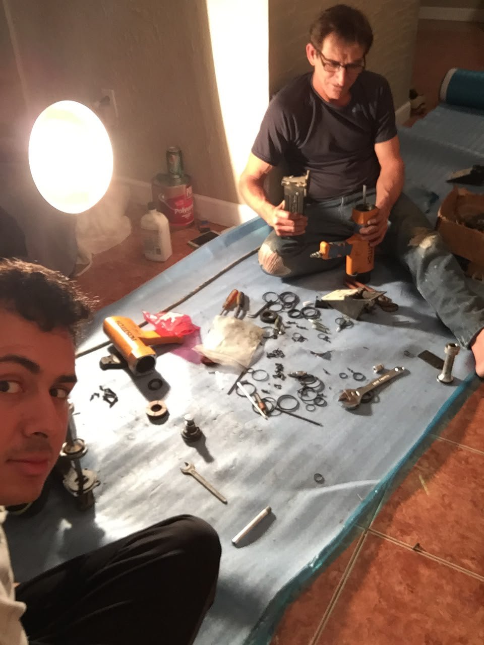 Two people working with tools on a protective blue covering in a photo from about ten years ago