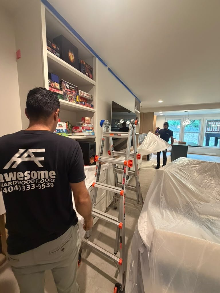 Awesome Hardwood Floors team covering furniture with protective plastic inside a home